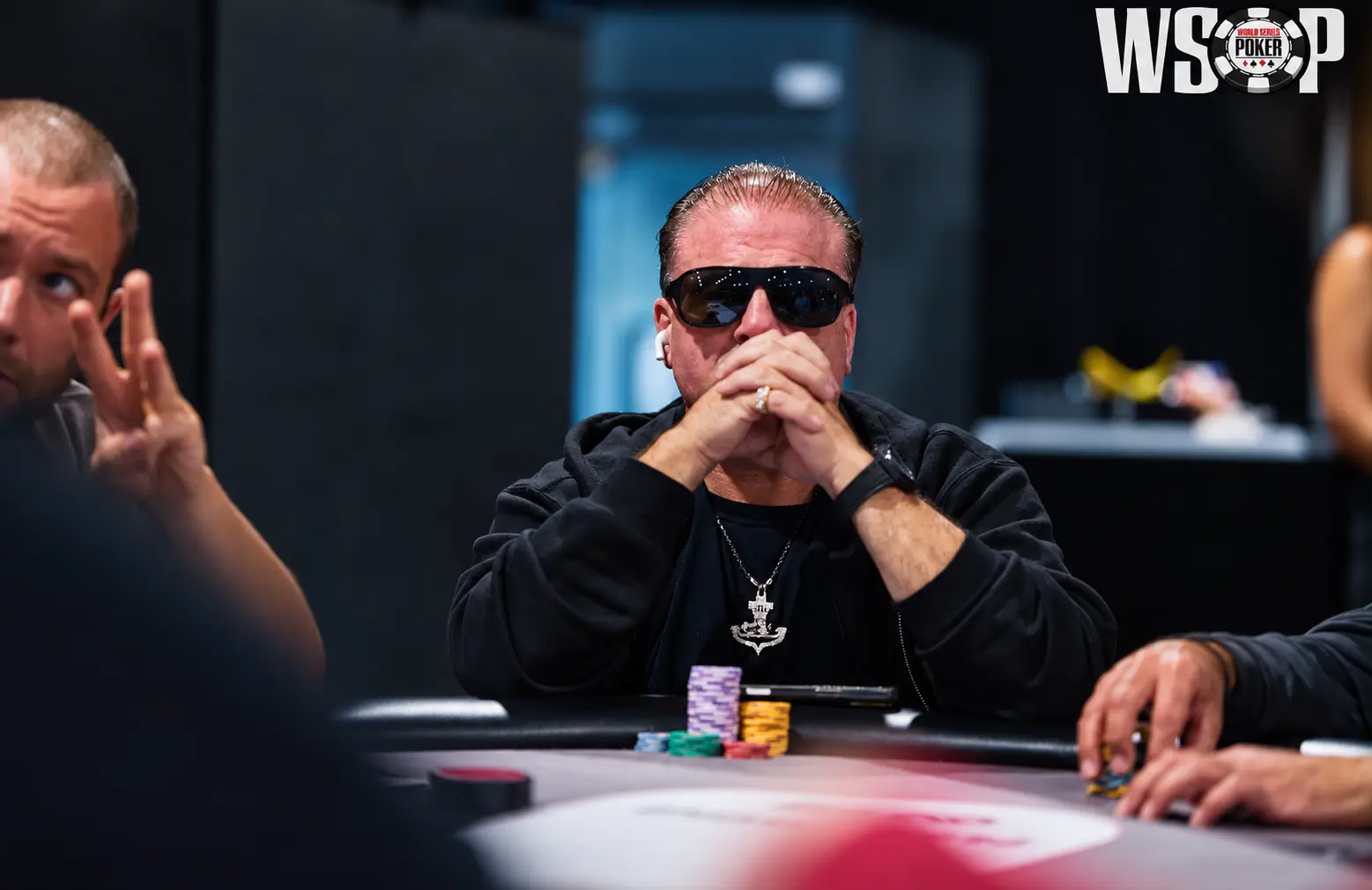 Tony Stax wearing sunglasses with his hands clasped at a tournament table, with the WSOP logo visible.