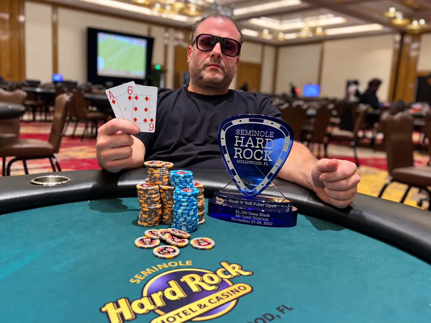 Anthony ‘Tony Stax’ Piacquadio holding his winning cards beside a Seminole Hard Rock tournament trophy.